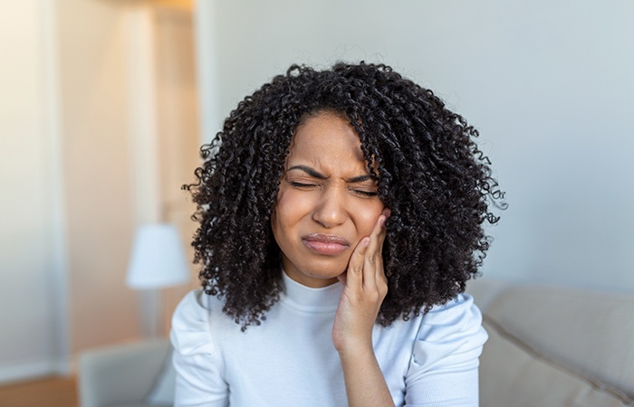 Woman in light blue shirt with tooth pain needing emergency dentist in Studio City, CA