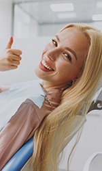 Female dental patient with blonde hair giving thumbs up