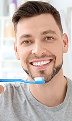 Man in grey shirt about to brush his teeth