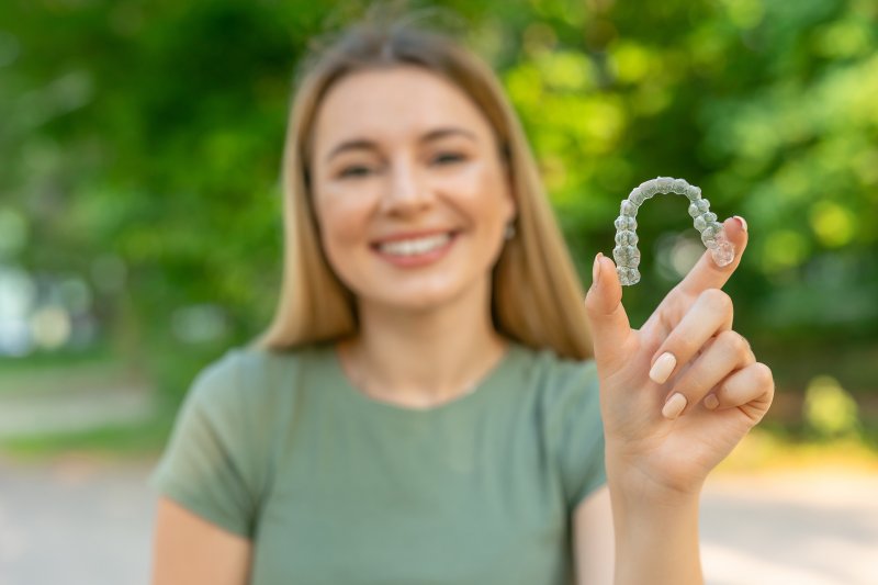 woman holding an Invisalign aligner outside 