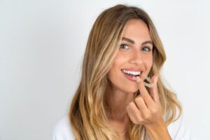 Smiling woman holding Invisalign aligner